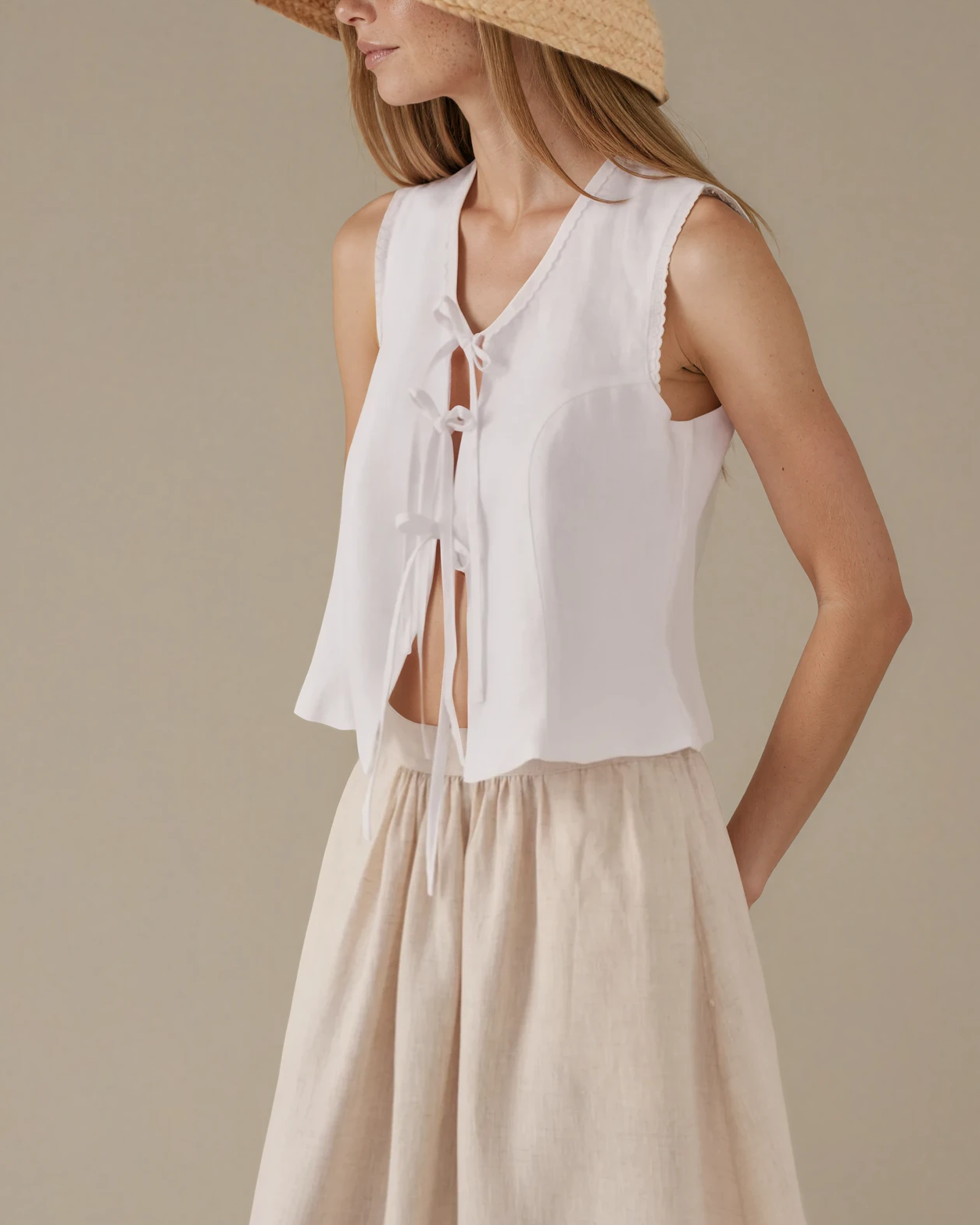 Woman wearing a white sleeveless top with embroidery details 